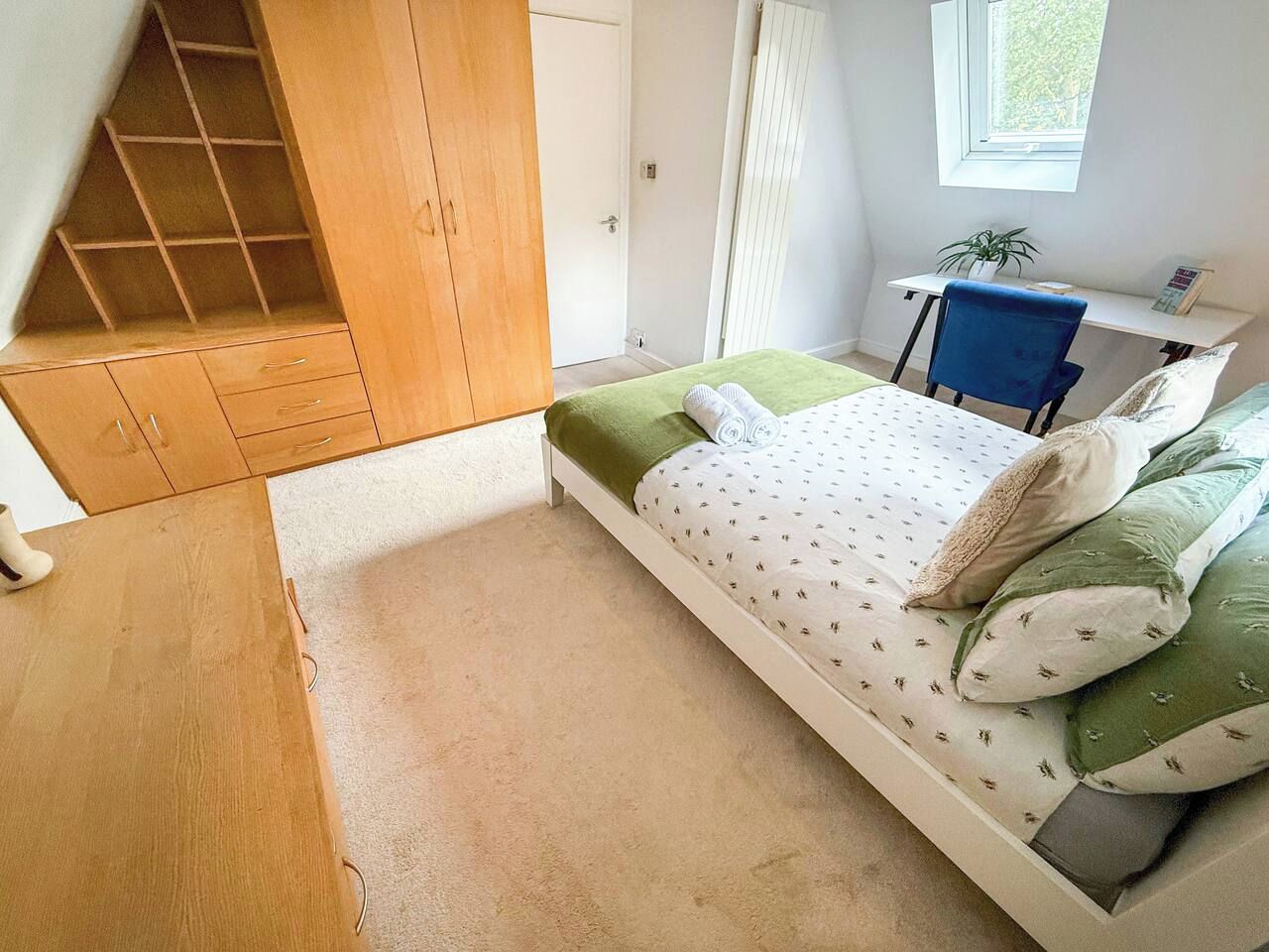 A bedroom with a bed, a desk, and a wardrobe.