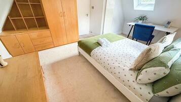 A bedroom with a bed, a desk, and a wardrobe.