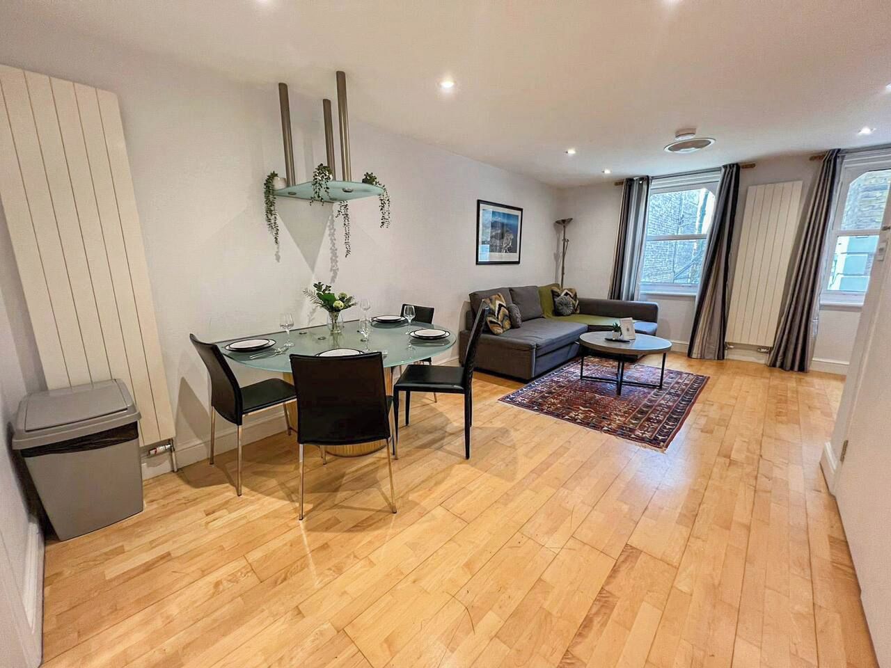 A modern living space with a dining area, a sofa, and a window with curtains.