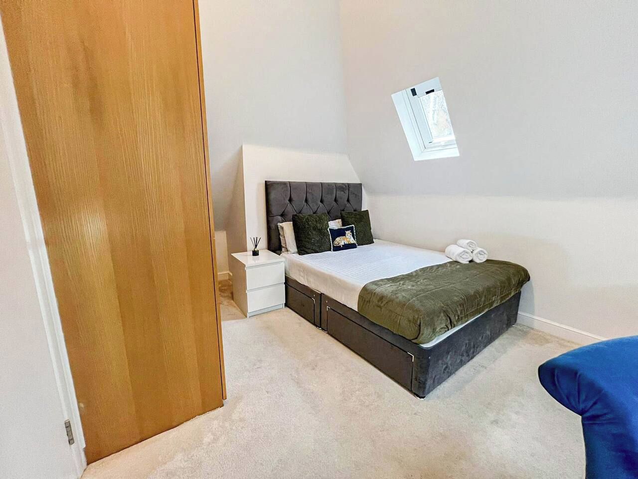 A bedroom with a bed, nightstand, and a wall-mounted light fixture.