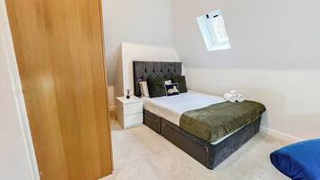 A bedroom with a bed, nightstand, and a wall-mounted light fixture.