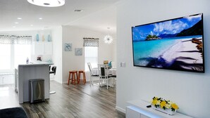 Una cocina moderna con isla integrada, armarios blancos y un refrigerador de acero inoxidable.