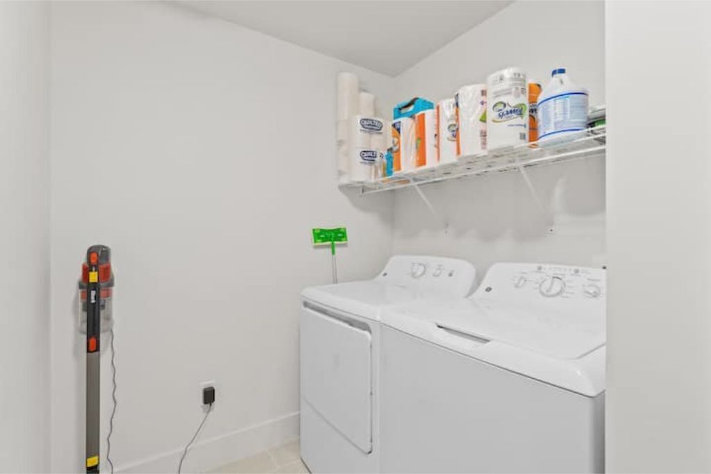 A laundry room with a washing machine, dryer, and shelves with cleaning supplies.
