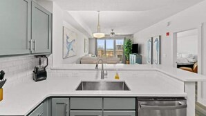 A modern kitchen with a central island, stainless steel appliances, and a view to a living area.