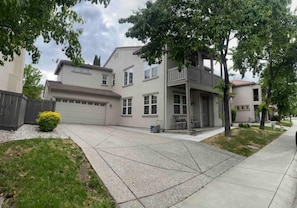 Una casa residencial de dos pisos con garaje, un porche cubierto y un césped cuidado.