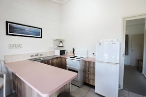 Kitchen features a stove, microwave, refrigerator, and sink, with a framed picture above the sink.