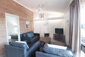 Relax in this stylish living area with a sofa set, coffee table, and TV on a stand.