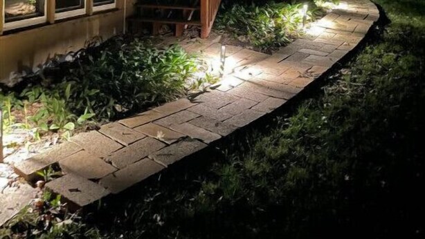 A house with a brick exterior, a wooden staircase, and a pathway leading to the front door. - The Fox Den (Ames)