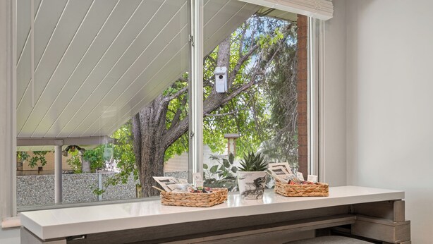 A modern kitchen with a large window, wooden cabinets, and a built-in bench with cushioned seats.