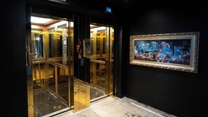 An elevator with glass doors and a framed painting on the wall. - Hotel Vuriloche Suites (San Carlos de Bariloche)
