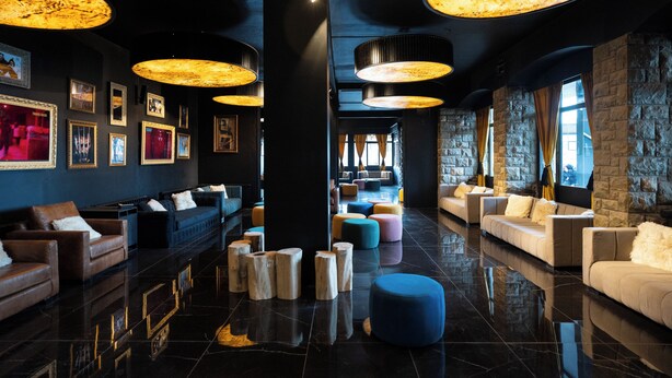 A modern lobby with plush seating, large wooden stools, and a polished floor. - Hotel Vuriloche Suites (San Carlos de Bariloche)