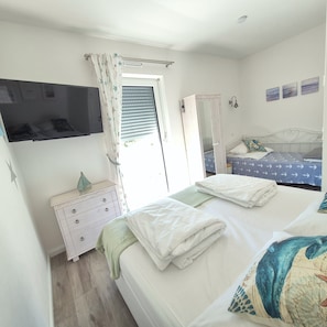 A bedroom with a bed, a dresser, a wardrobe, a TV, and a window with curtains.