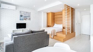 A modern bedroom with a bed, a TV, and a seating area with sofas. - VIVA  Marquês Studio (Porto)