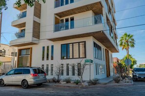 Stylish building with white and wood paneling, large windows, and balconies.