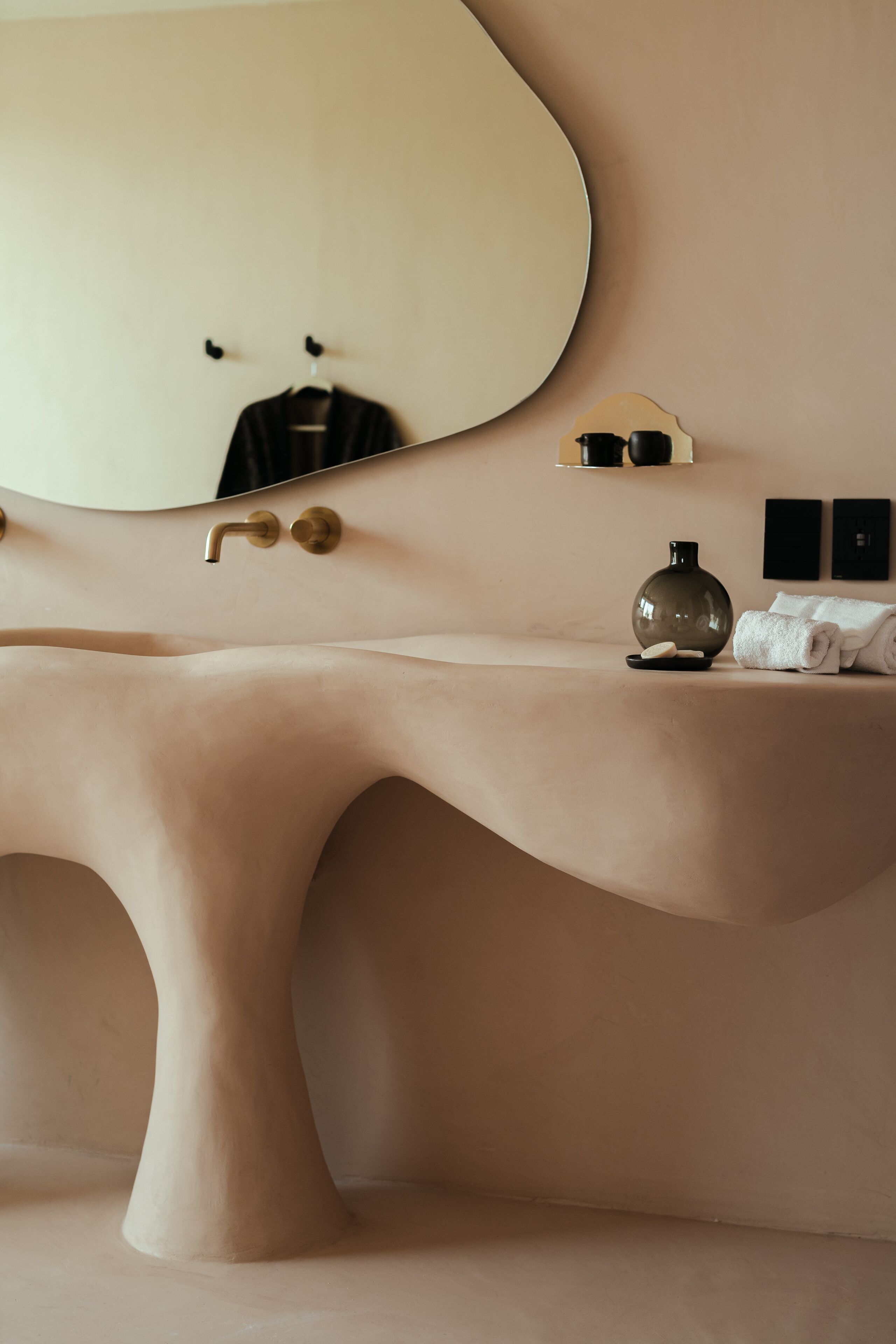 Un baño con un original diseño de lavamanos curvo, un espejo grande y un perchero para toallas.
