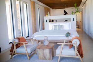 A modern bedroom with a large bed, two side tables, and a chair. - Republica Pagana - Adults Only (La Paz)