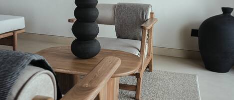 A minimalist room with a wooden chair, a small table, and a large black vase.