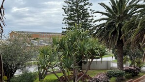 Un jardin aménagé avec différents arbres et arbustes, un chemin pavé et un bâtiment en arrière-plan.