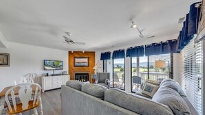 A living room with a sofa, a dining table with chairs, a fireplace, and large windows with curtains. - Libby's Lake View on Smith Mountain Lake  - Inquire about long term rentals! (Moneta)