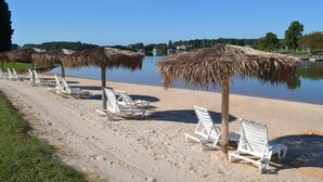 A beach with white lounge chairs and thatched umbrellas. - Libby's Lake View on Smith Mountain Lake  - Inquire about long term rentals! (Moneta)