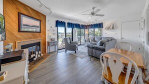 A modern living room with a fireplace, a dining area with a wooden table and chairs, and a balcony with a view. - Libby's Lake View on Smith Mountain Lake  - Inquire about long term rentals! (Moneta)