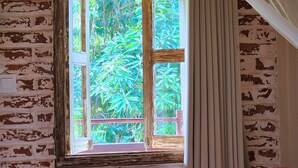 A room with a brick wall, a window with a wooden frame, and a curtain. - Danaya's villa (Ubud)
