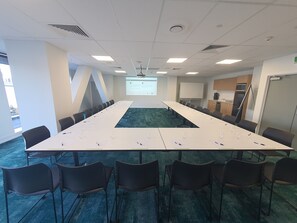 A conference room with a long table, chairs, a projector screen, and a presentation on the wall. - La Quinta By Wyndham Ellerslie Auckland (Auckland)