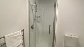 Un bagno moderno con doccia vetrata, un water bianco e un portaserviti con asciugamani bianchi.