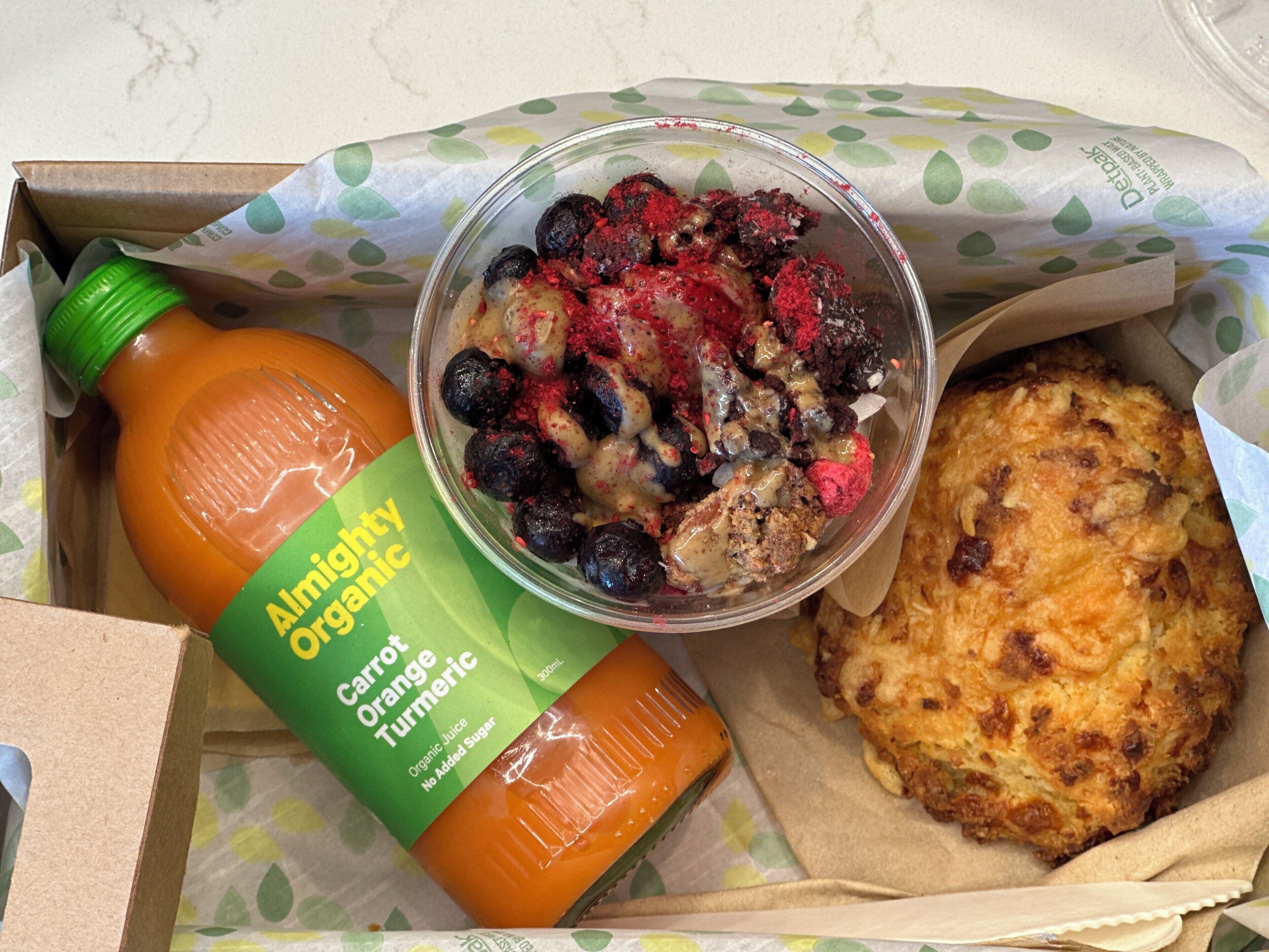 A meal with a juice bottle, a dessert, and a biscuit in a box.