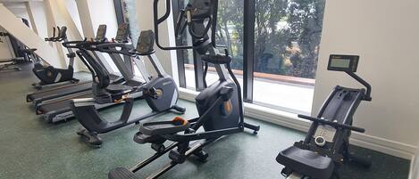 A gym with treadmills, elliptical machines, and a bench press.