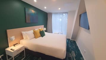 A neatly arranged hotel room with a large bed, bedside table, and a painting on the wall.