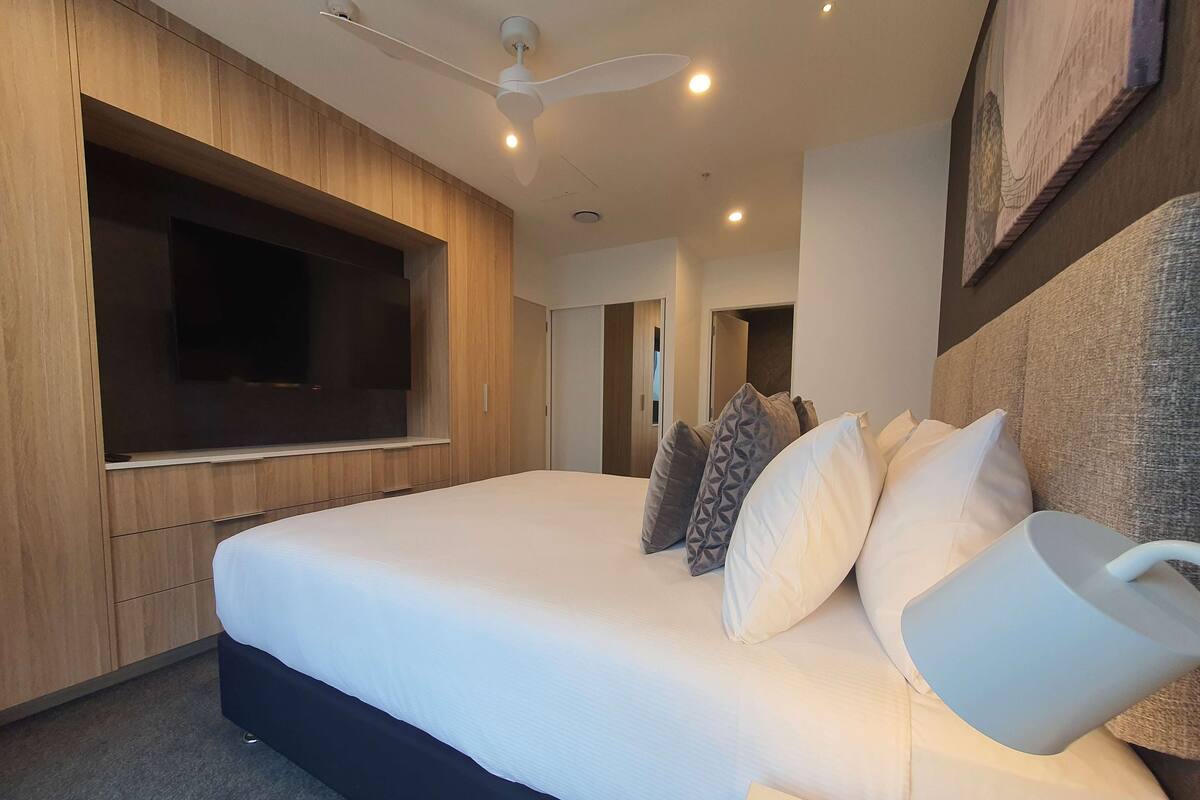 Ein modernes Hotelzimmer mit einem großen Bett, einem flachbildfernseher an der Wand und einem Deckenventilator.