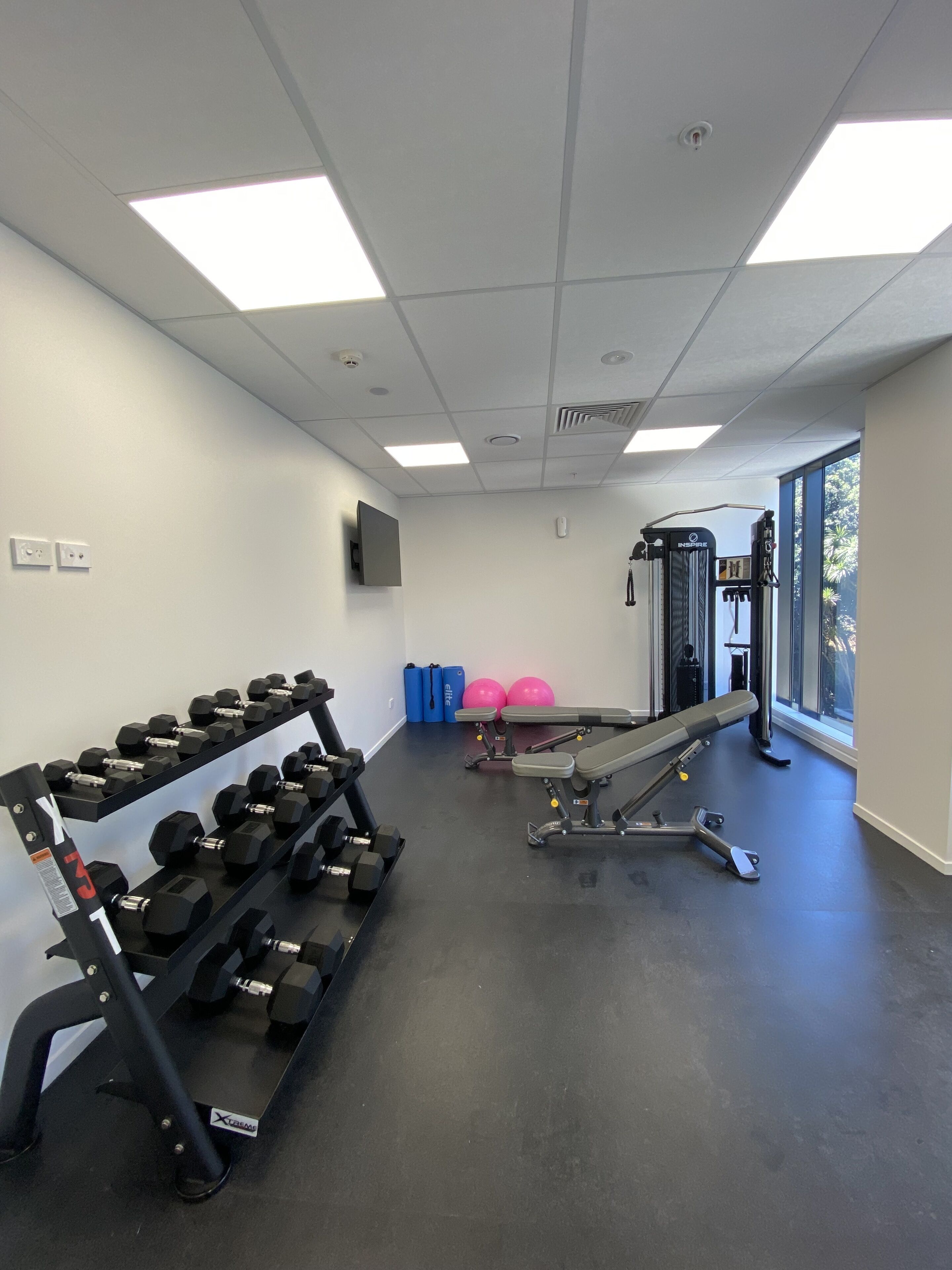 A gym with weightlifting equipment, exercise balls, and a bench press.