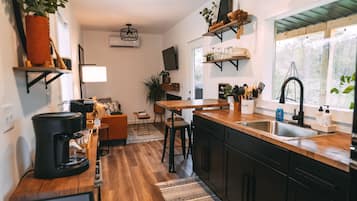 Een moderne keuken met houten vloeren, een centraal eiland en zwarte kastjes.