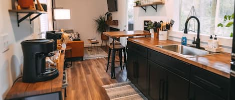 Cocina moderna con suelo de madera, una isla central y armarios negros.