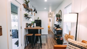 Une cuisine moderne avec un plan de travail en bois, des tabourets de bar noirs et un coin repas.