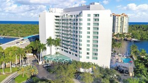 Un hotel moderno con piscina, rodeado de palmeras y vistas al océano.