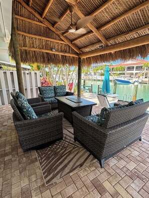 A covered outdoor seating area with wicker furniture and a view of a marina. - Promo 15% off til Dec 23, 3br 3BA, Cabana Club Pool , Dock, Tiki Hut (Key Colony Beach)