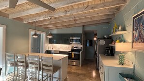 Cozinha moderna com ilha central, eletrodomésticos de aço inoxidável e teto de madeira.