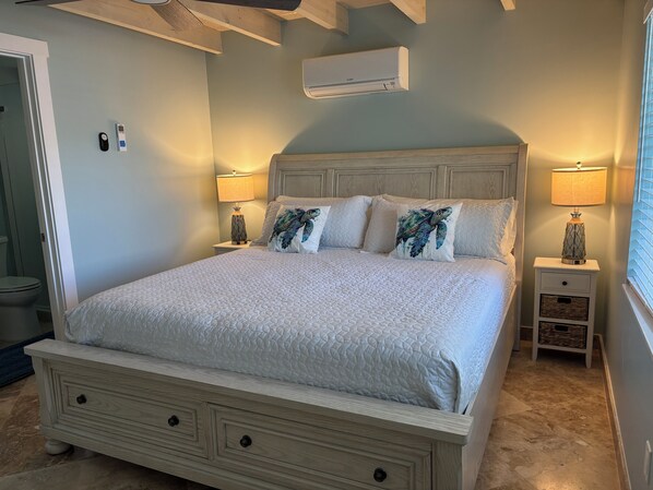 A bedroom with a bed, bedside tables, an air conditioner, and a window. - Promo 15% off til Dec 23, 3br 3BA, Cabana Club Pool , Dock, Tiki Hut (Key Colony Beach)