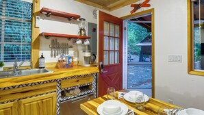 A compact kitchen with a wooden countertop, a built-in oven, and a red door leading to an outdoor area. - Adorable A-Frame Cabin, Steps to Lake Cushman! (Hoodsport)