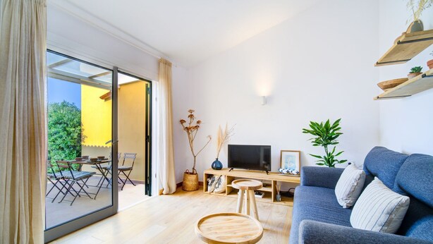 A modern living room with a sofa, TV, and a dining area with chairs and a table. - Surmar - Apartment with pool in Cap d'Artrutx (Ciutadella de Menorca)