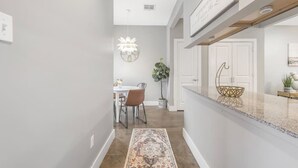 Une cuisine moderne avec des meubles blancs, un plan de travail en granit et un luminaire suspendu.