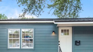 Une maison à l’extérieur bleu, avec une porte blanche et une boîte aux lettres portant l’inscription « B 222 ».