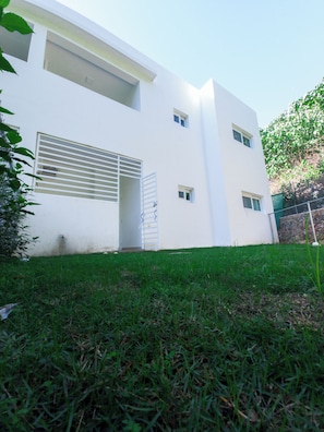 A modern white building with a flat roof, a garage door, and a small door. - 2JA Management Group - White Hill Condos (Sosúa)