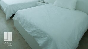 Una habitación de hotel con dos camas, un ventilador de techo y dos ventanas con persianas.