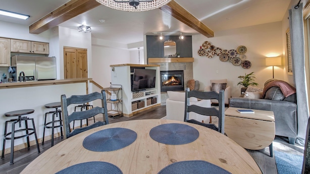 Een moderne keuken met houten kastjes, een inbouwkoelkast en een eethoek met een ronde tafel en stoelen.