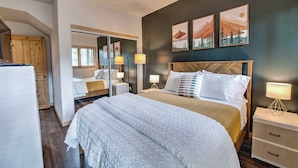 Een moderne hotelkamer met een groot bed, nachtkastjes, een kledingkast en een spiegel.