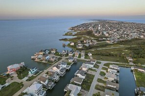 An aerial view of a coastal residential area with houses, a marina, and a large body of water.