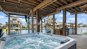 Ein Whirlpool unter einer Holzpergola mit Blick auf einen Hafen und Häuser.